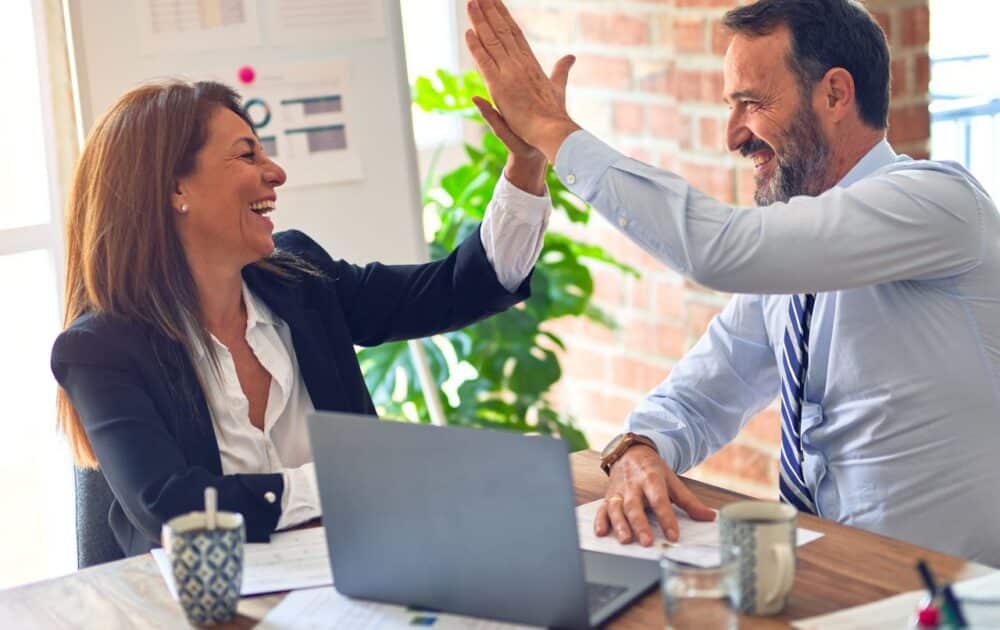 Zwei Personen klatschen sich in die Hand und drücken Freude aus.