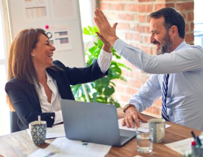Zwei Personen klatschen sich in die Hand und drücken Freude aus.